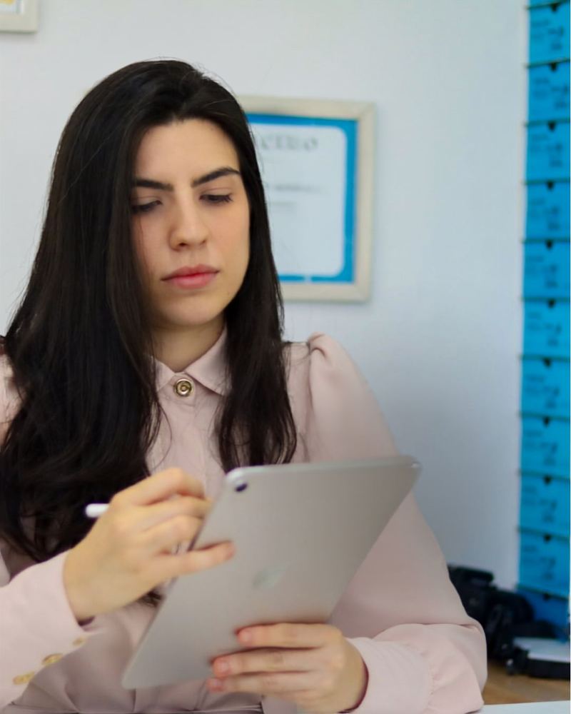 Dra. Júlia Reis em seu consultório, com diplomas de formação ao fundo